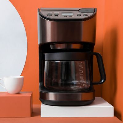 Kaffeemaschine vor orangenem Hintergrund und Tasse
