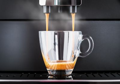 Kafee läuft aus der Maschine in eine durchsichtige Tasse