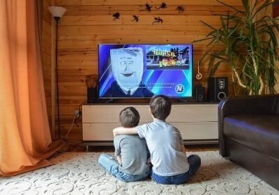 children sitting close to the TV